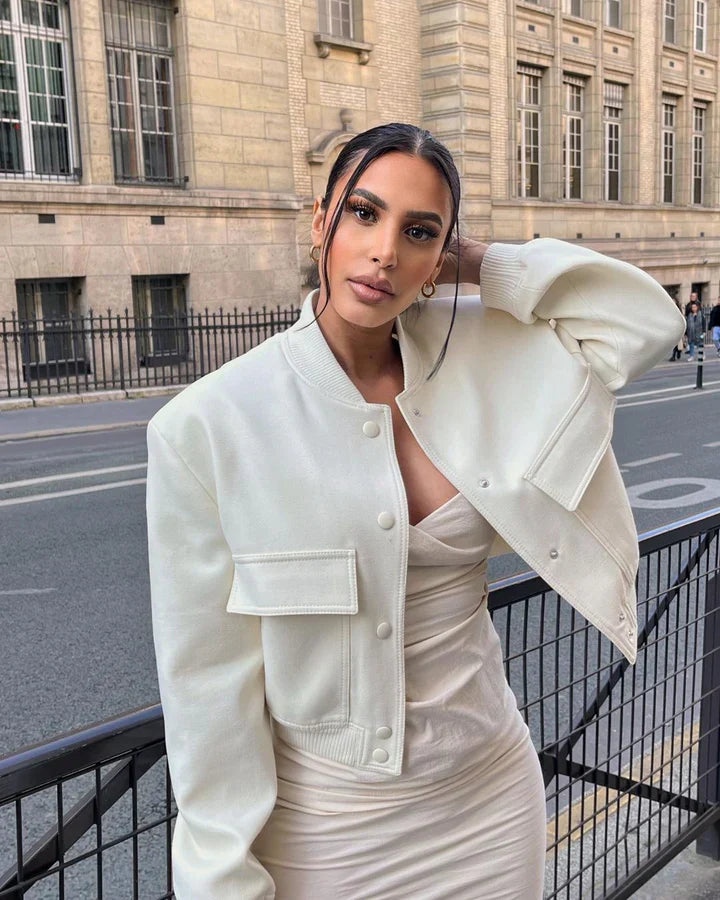 Woman in a white outfit standing on a street with a building in the background