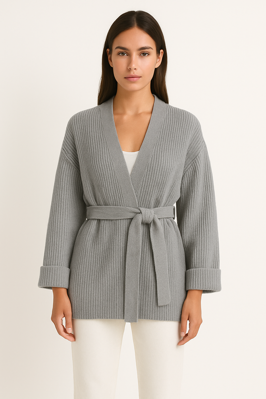 Woman wearing a gray ribbed cardigan with a belt on a beige background