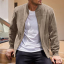Man wearing a beige jacket over a white shirt, standing next to a car.