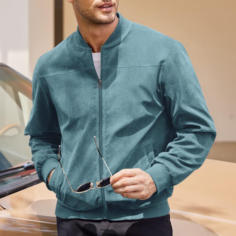 Man wearing a teal jacket holding sunglasses, standing next to a car.