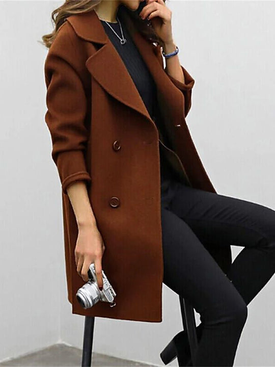 Person wearing a brown coat holding a camera against a white background